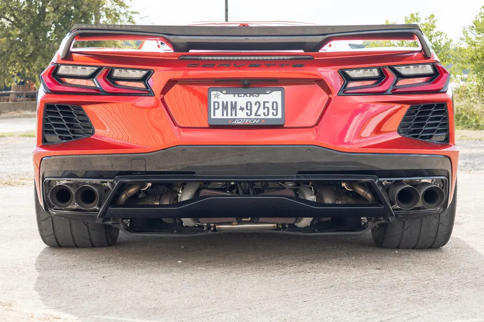 Rear view of a red C8 Corvette with a custom twin-turbo setup and quad exhaust tips, showcasing performance modifications.