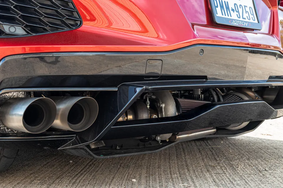 Close-up of a red Corvette C8 rear showing aftermarket turbocharger, air filter, and dual exhaust tips.