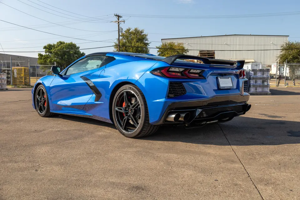 Rear three-quarter view of a blue Corvette C8.R with a large rear wing, aggressive diffuser, and quad exhaust tips.