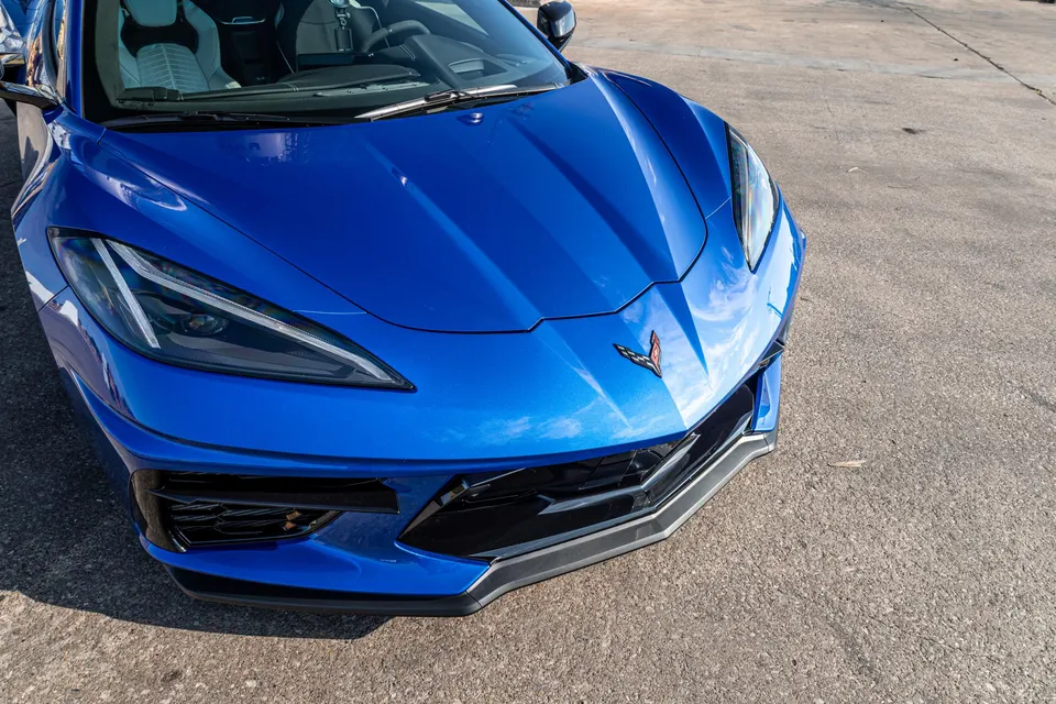 Front view of a bright blue Chevrolet Corvette C8, showcasing its sleek design and aggressive front bumper.