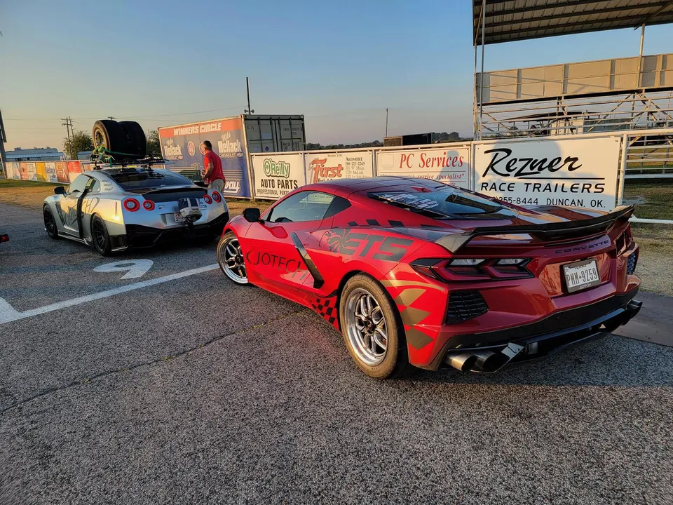 Nissan GT-R and Jotech-liveried C8 Corvette at a drag strip staging lane, ready for a race.