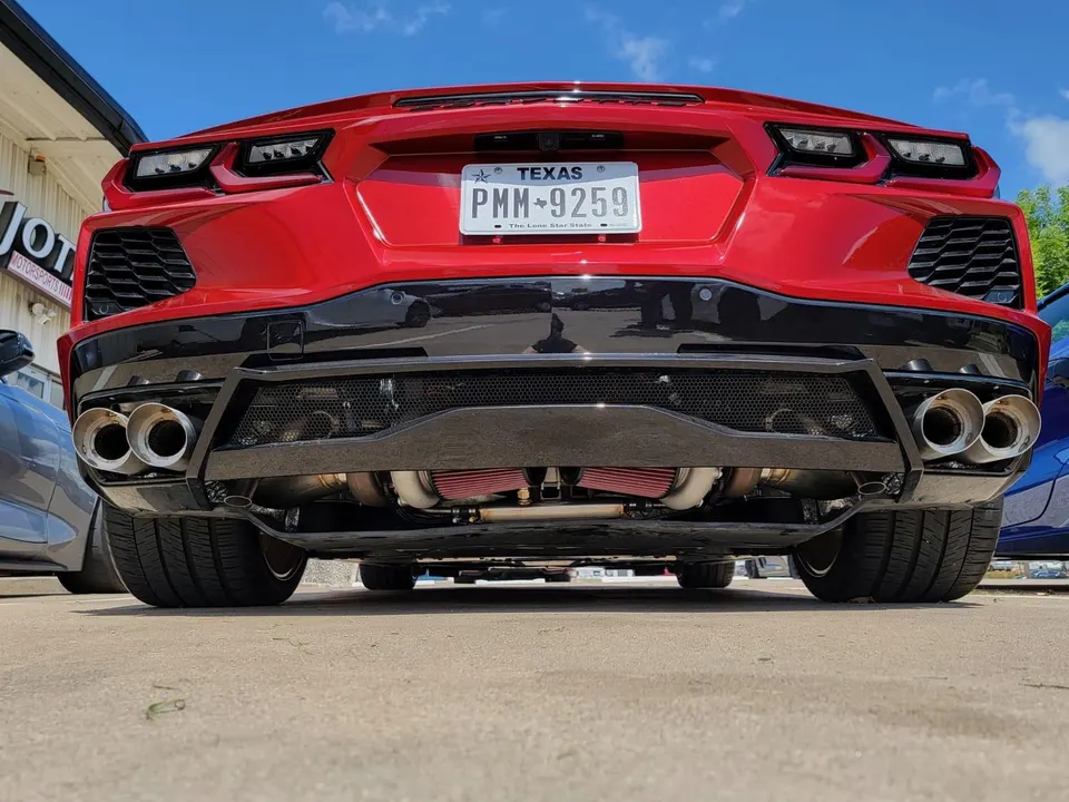 Rear view of a red Corvette C8 with a custom exhaust and visible turbocharger setup.