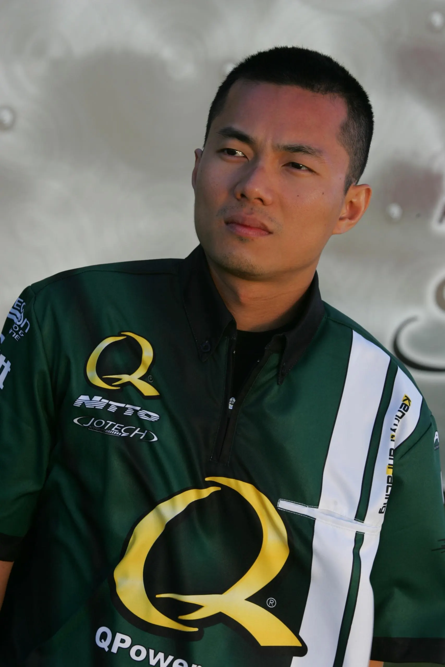 Portrait of a man wearing a green and white Jotech Motorsports racing shirt with Nitto and QPower logos.