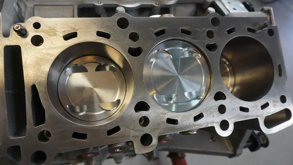 Close-up view of an engine block with new pistons installed, showcasing internal engine components during a build.