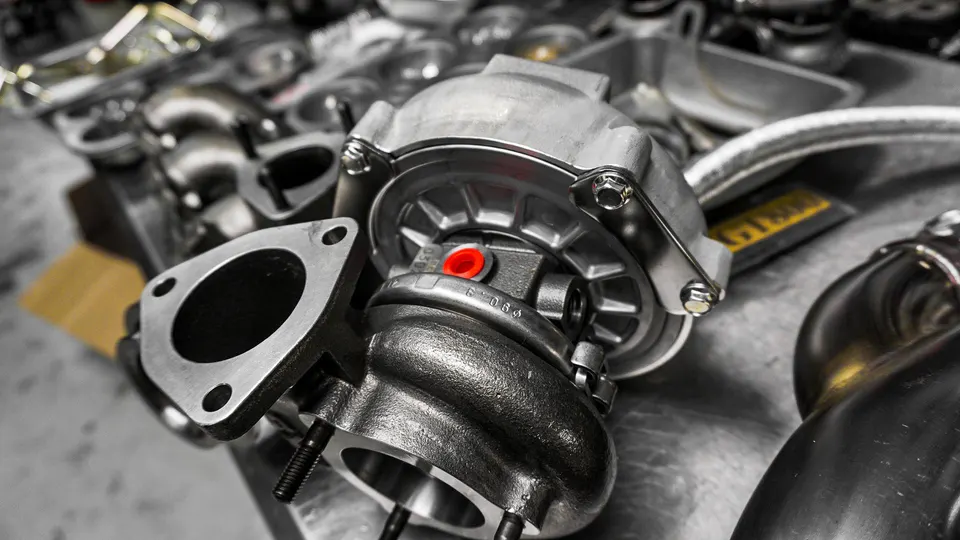 Close-up of a new performance turbocharger on a workbench in a tuning shop, ready for installation.