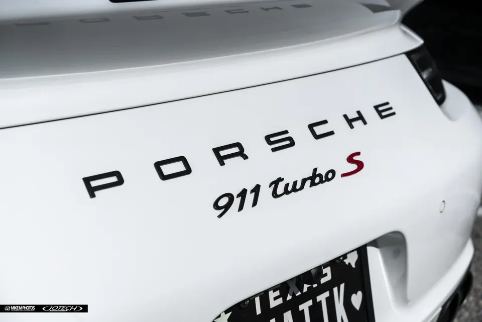 Close-up of the rear badge on a white Porsche 911 Turbo S, showing the model designation.