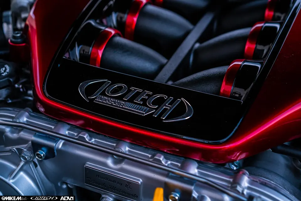Close-up of a Jotech custom engine bay featuring a red and black intake manifold and polished engine components.
