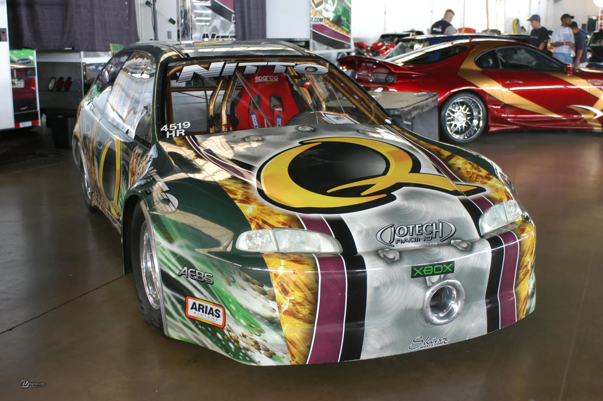 Custom built Honda Civic drag car with a vibrant livery, roll cage, and racing seat on display at an event.