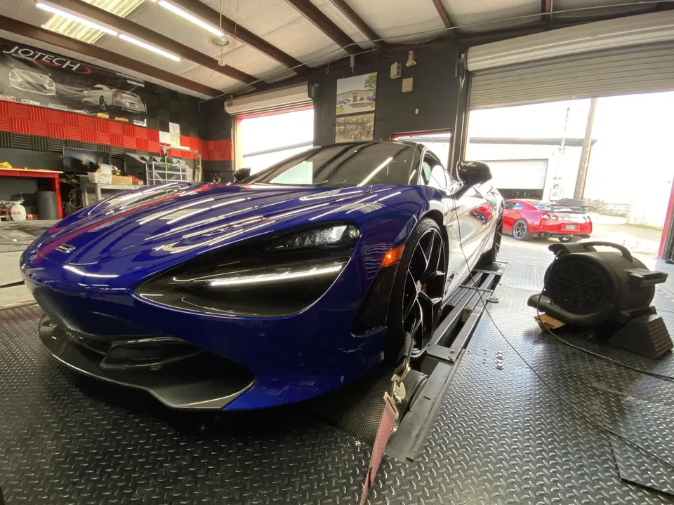 Blue McLaren 720S on a dyno at Jotech Motorsports with a red Nissan GT-R in the background.