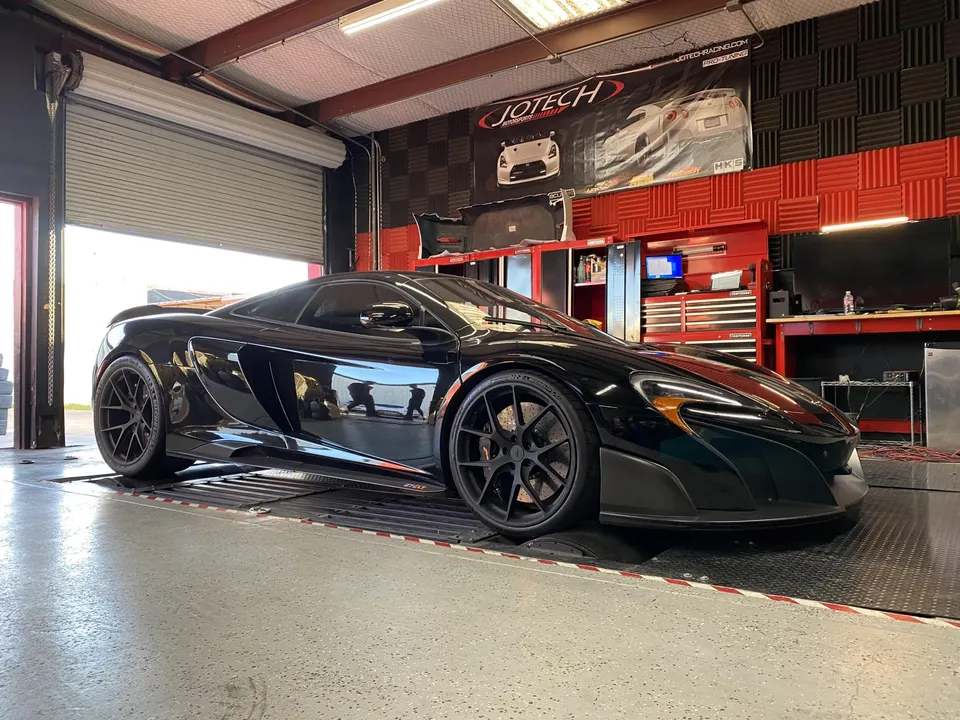 A black McLaren supercar on a dyno at Jotech Motorsports for performance tuning and horsepower measurement.