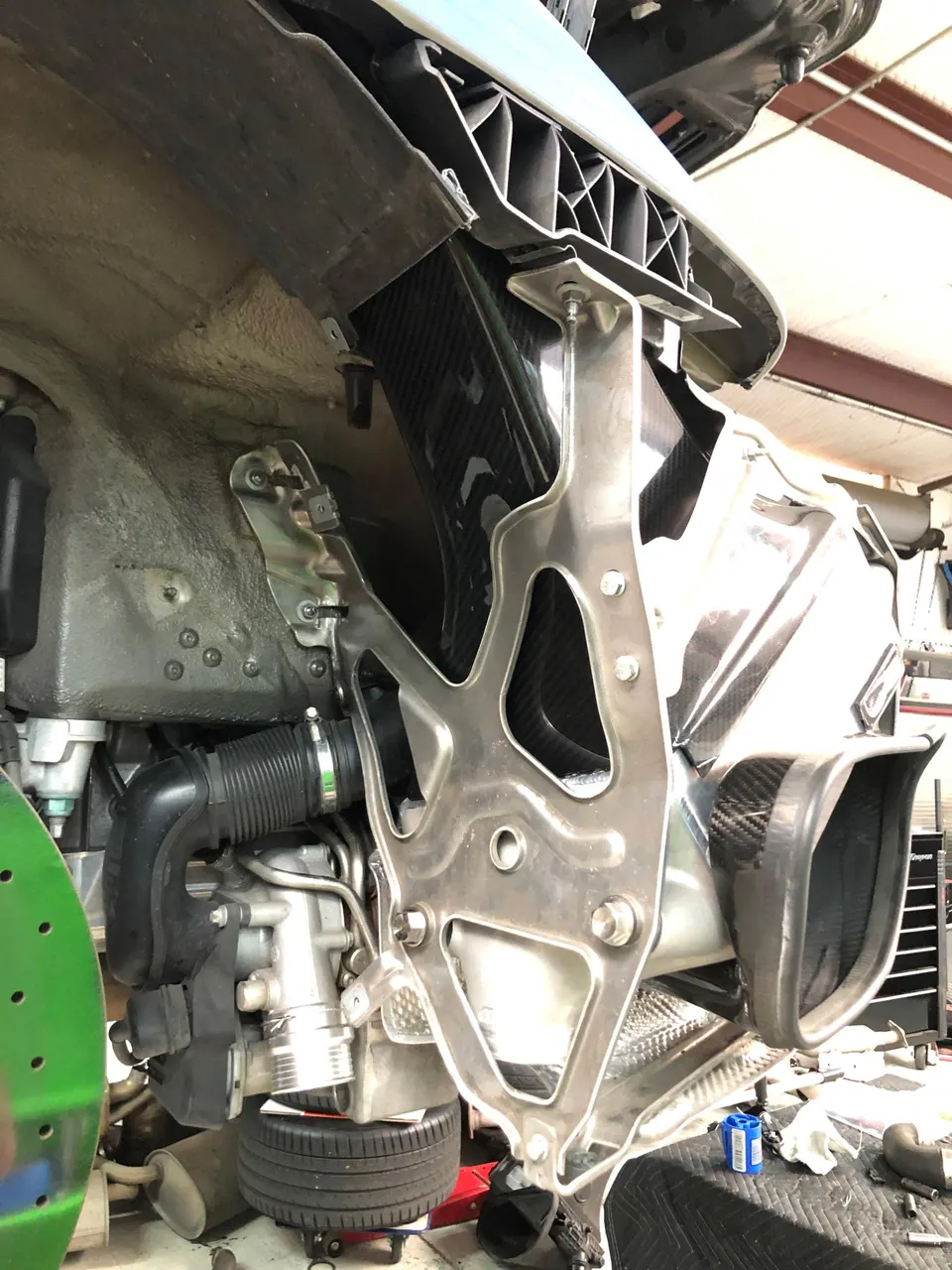A McLaren's front end disassembled in a shop, revealing carbon fiber air intake components and internal structure.