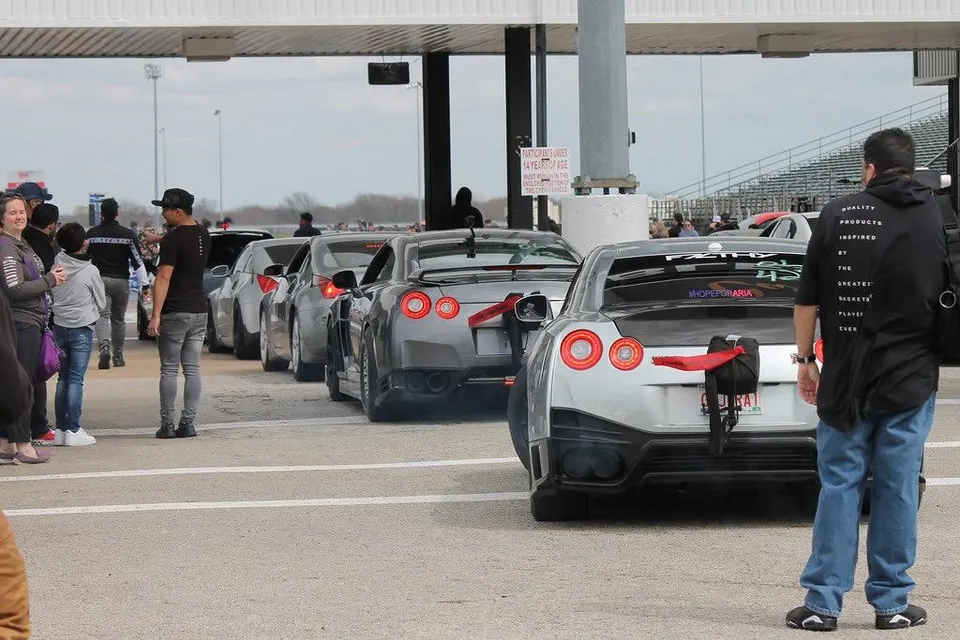 Nissan GT-Rs lined up in the staging lanes at a drag strip, with spectators watching the race cars.