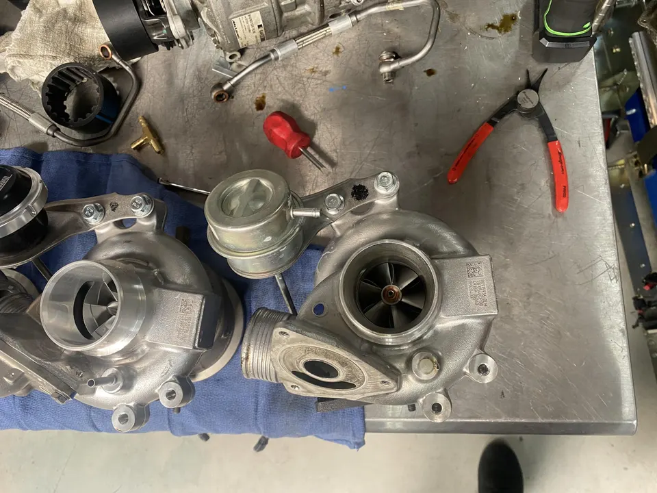 Two turbochargers and various tools laid out on a metal workbench in a performance tuning shop.
