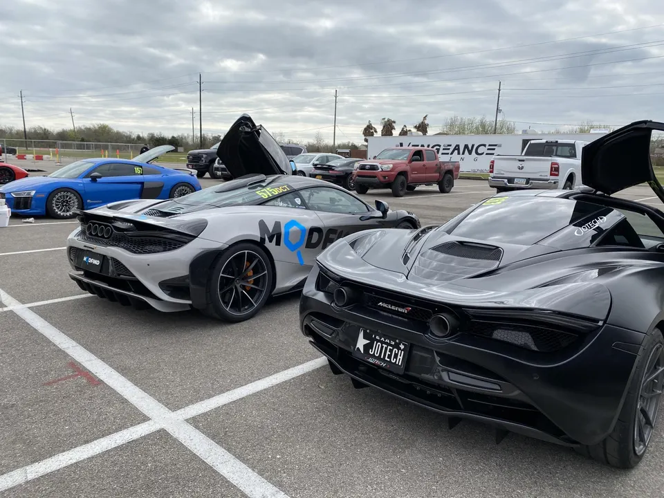 McLaren 720S and Audi R8 supercars parked in the staging lane at a track event, with Jotech branding visible.