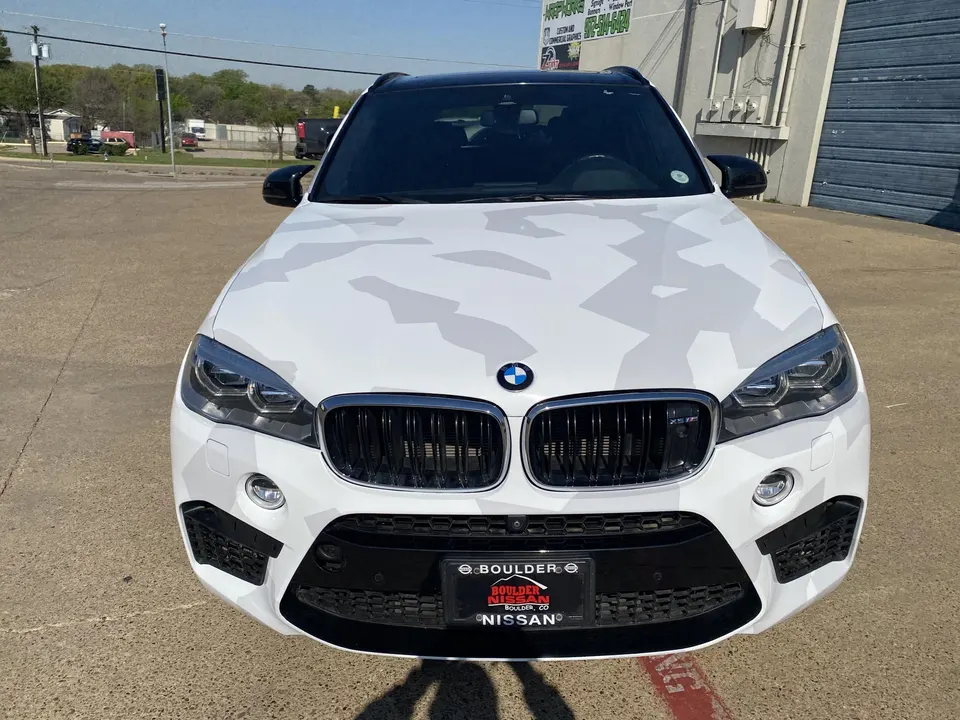Front view of a white BMW X5 SUV with a distinctive white and grey camouflage wrap, parked outdoors.