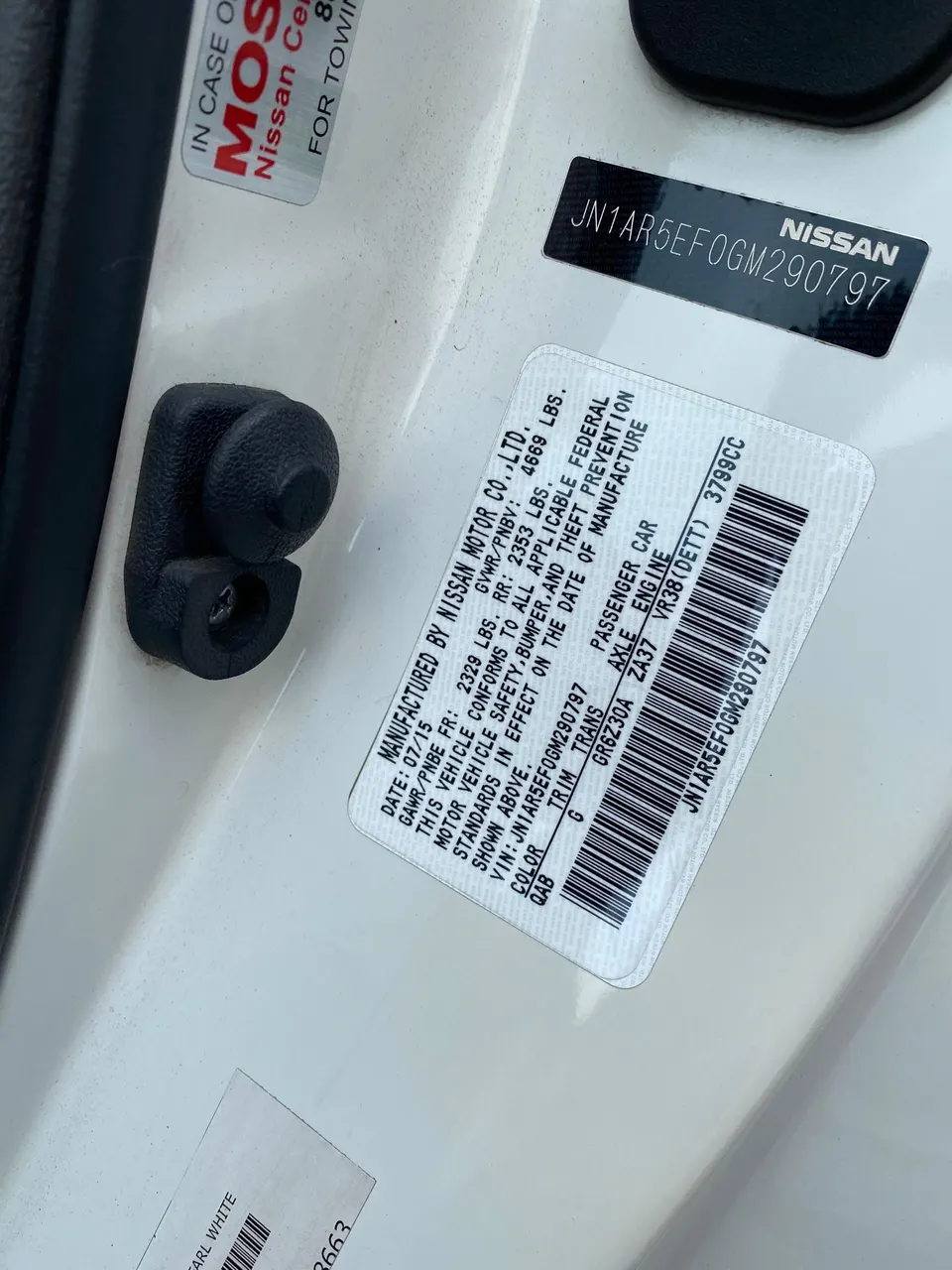 Close-up of a Nissan vehicle identification number (VIN) and manufacturing information label on the door jamb.