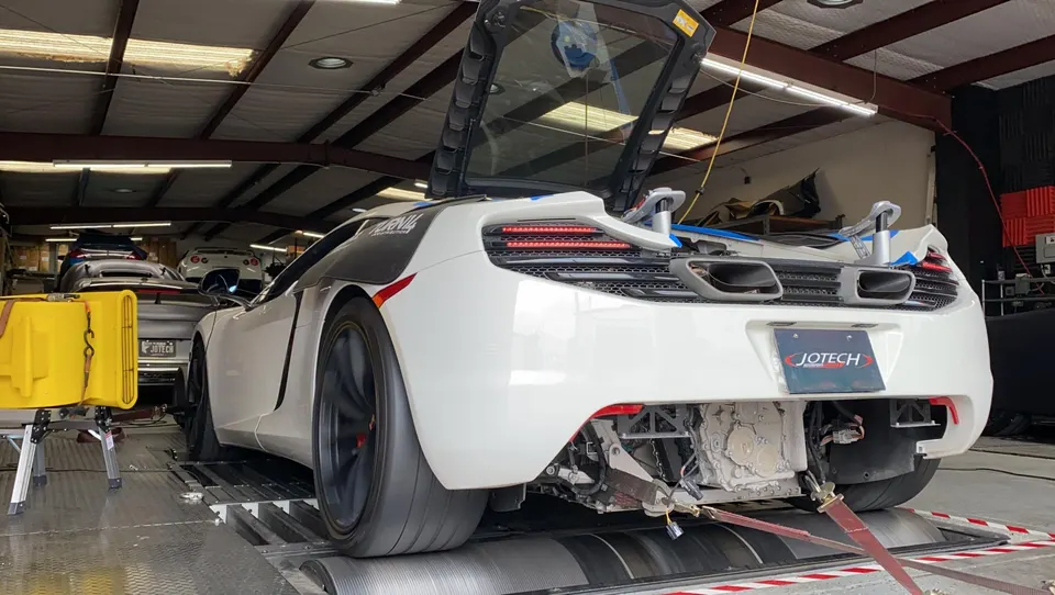White McLaren supercar strapped to a dyno at Jotech Motorsports for performance testing and tuning.