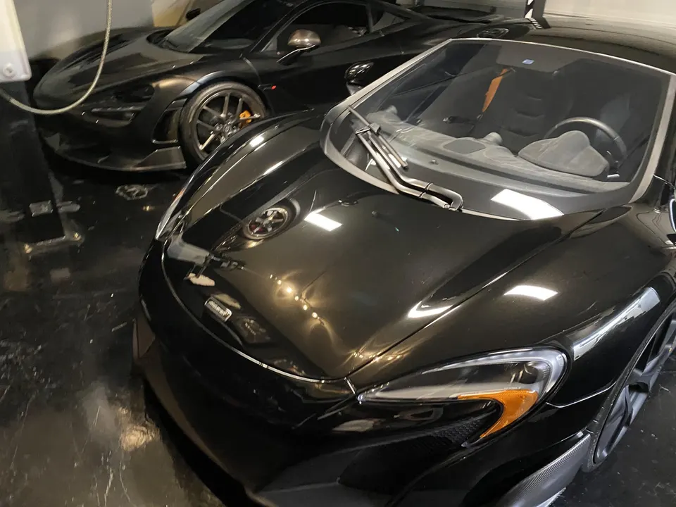 Two black McLaren supercars parked side-by-side in a clean garage, showcasing their sleek design.