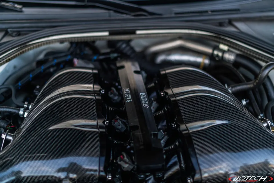 Close-up of a high-performance engine bay featuring a carbon fiber intake manifold and Alpha Performance fuel rails.