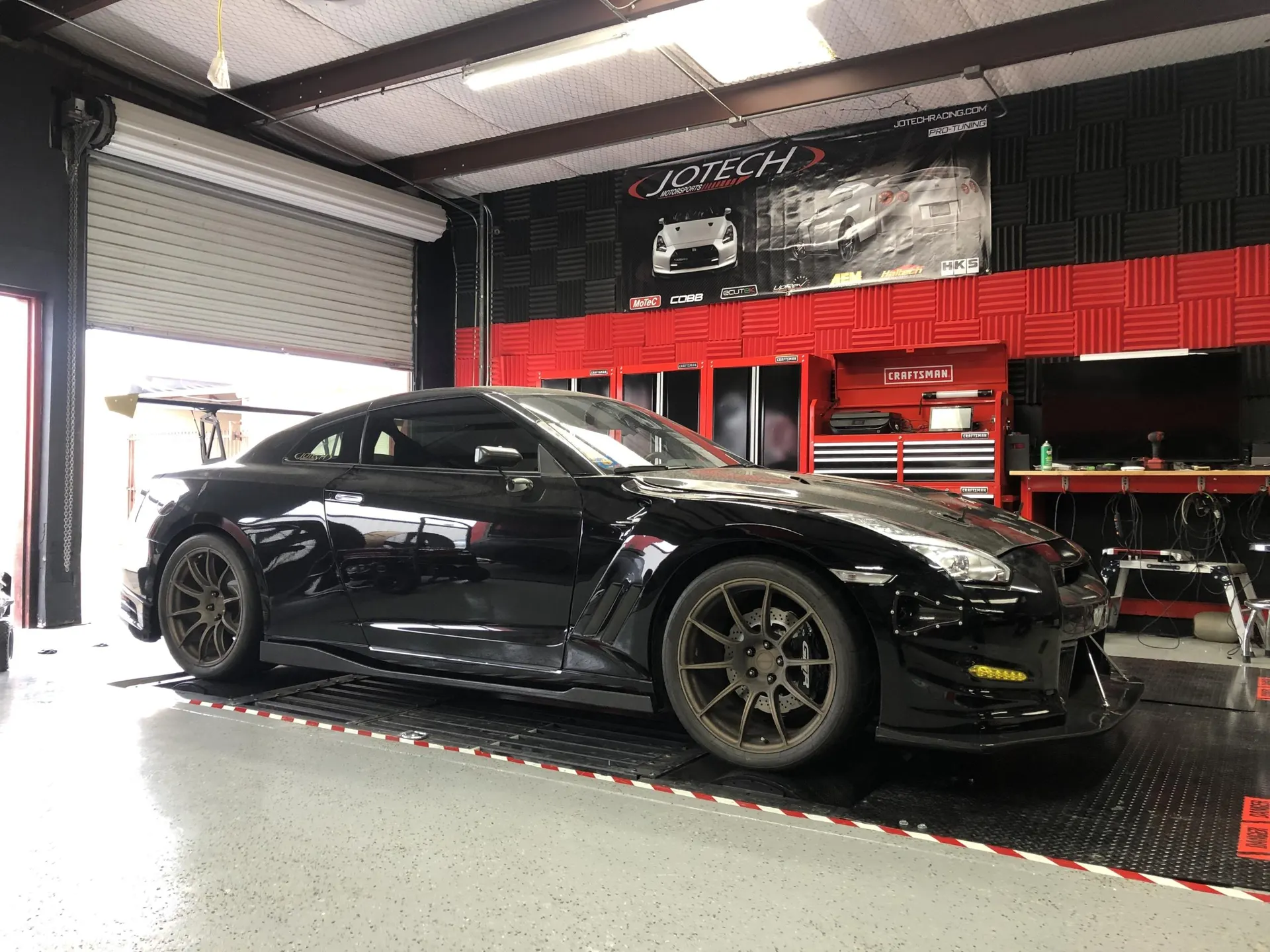 Black Nissan GT-R on a dyno at Jotech Motorsports tuning shop.