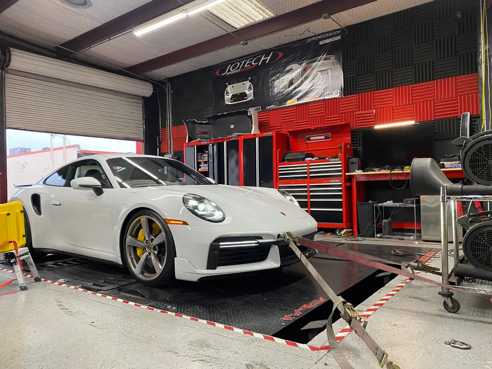 White Porsche 911 Turbo S strapped to a dynamometer at Jotech Motorsports for performance tuning.