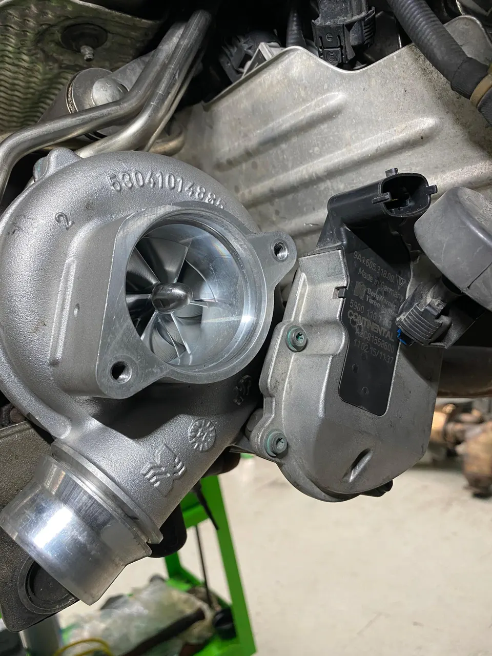Close-up of a new turbocharger with its compressor wheel visible, ready for installation in an engine bay.