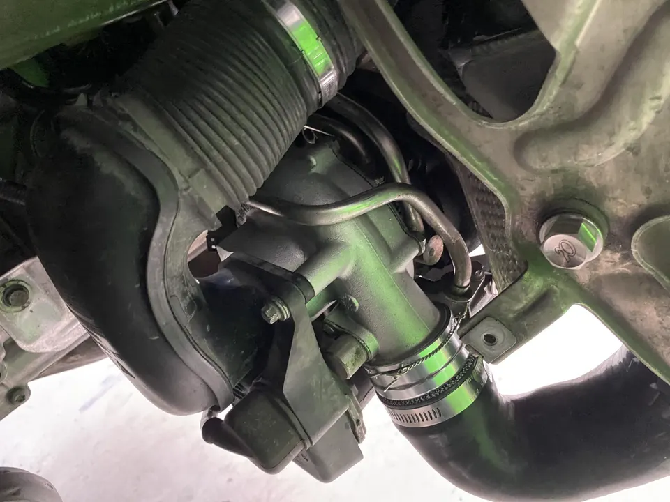 Close-up of an automotive engine bay showing intake hoses and clamps connected to a metal component.