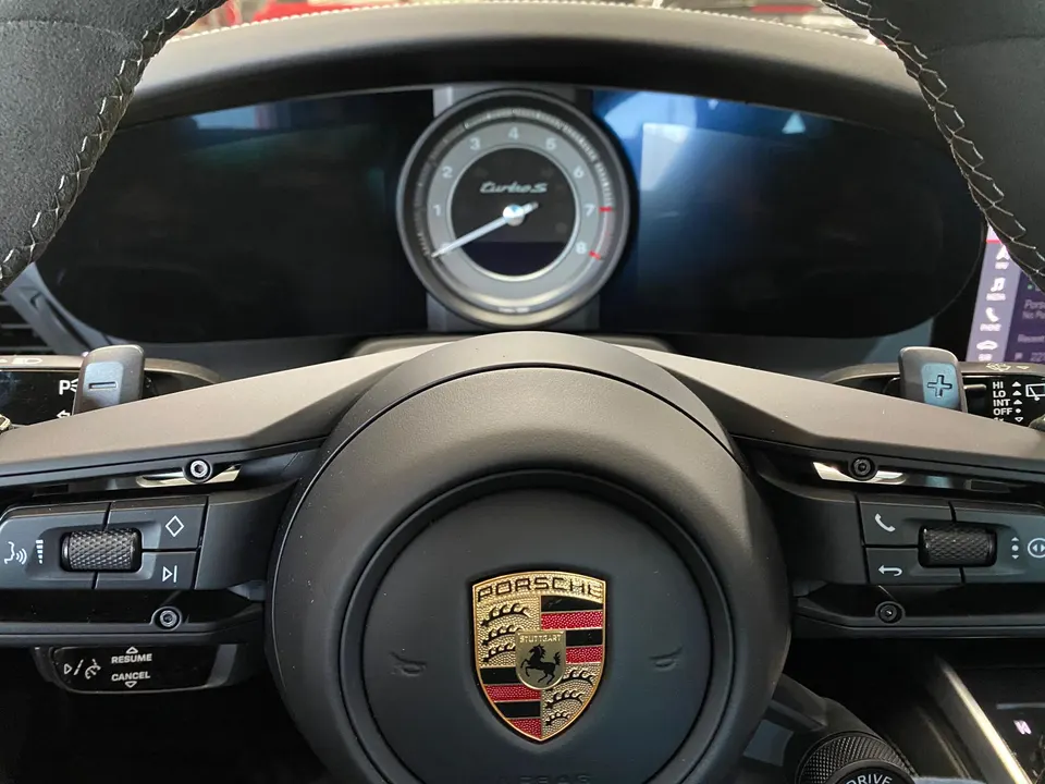 Close-up of a Porsche Turbo S steering wheel and digital instrument cluster, showcasing the interior details.