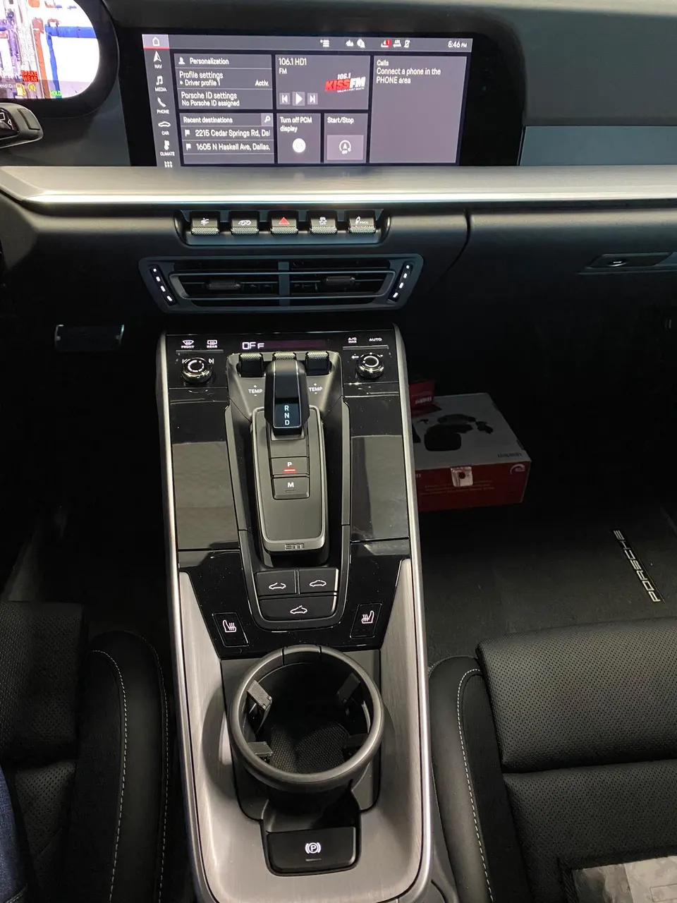 Detailed view of a Porsche interior, showing the center console, infotainment screen, shifter, and cup holder.