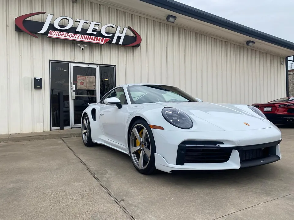 White Porsche 911 Turbo S parked outside Jotech Motorsports performance tuning shop.