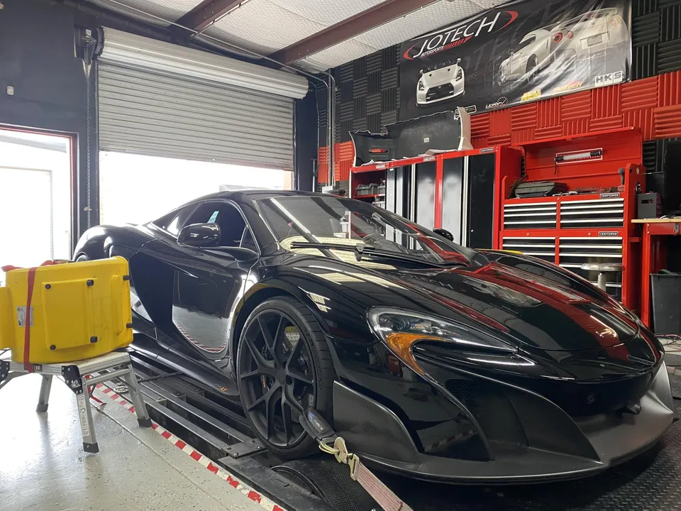 Black McLaren supercar strapped to a dyno at Jotech Motorsports for performance tuning and horsepower measurement.