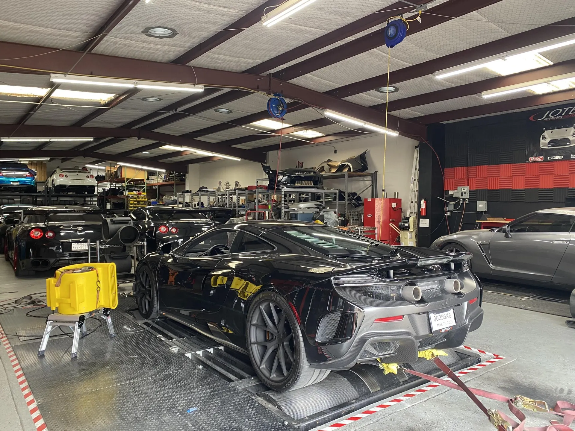 Black McLaren 650S strapped to a dynamometer for performance tuning at Jotech Motorsports shop.