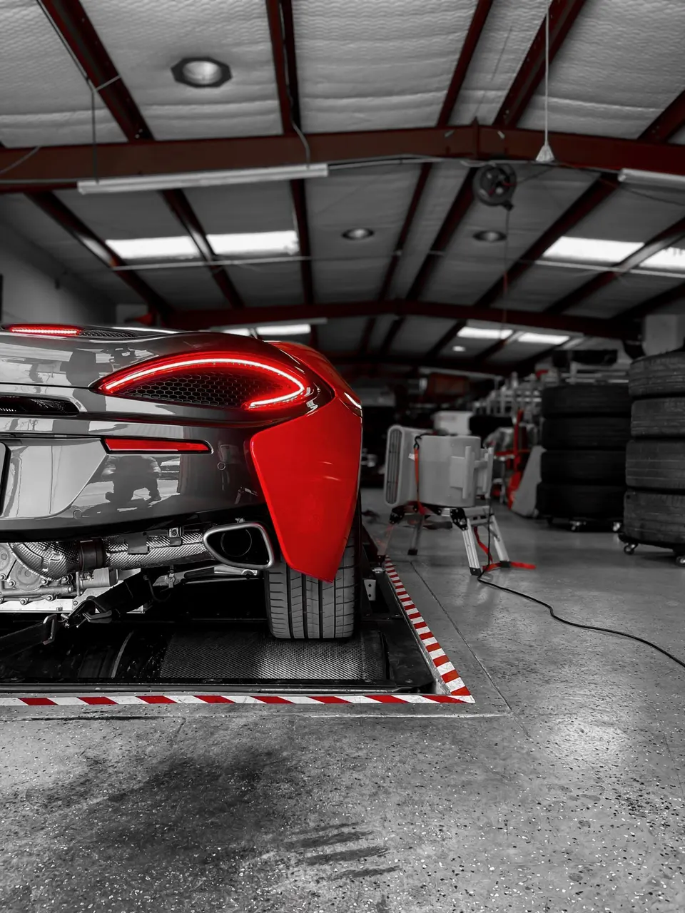 A McLaren sports car on a dynamometer in a performance tuning shop, with its red taillights illuminated.