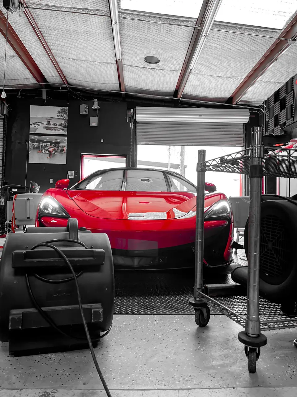 A red McLaren supercar on a dyno in a performance tuning shop, ready for power testing.