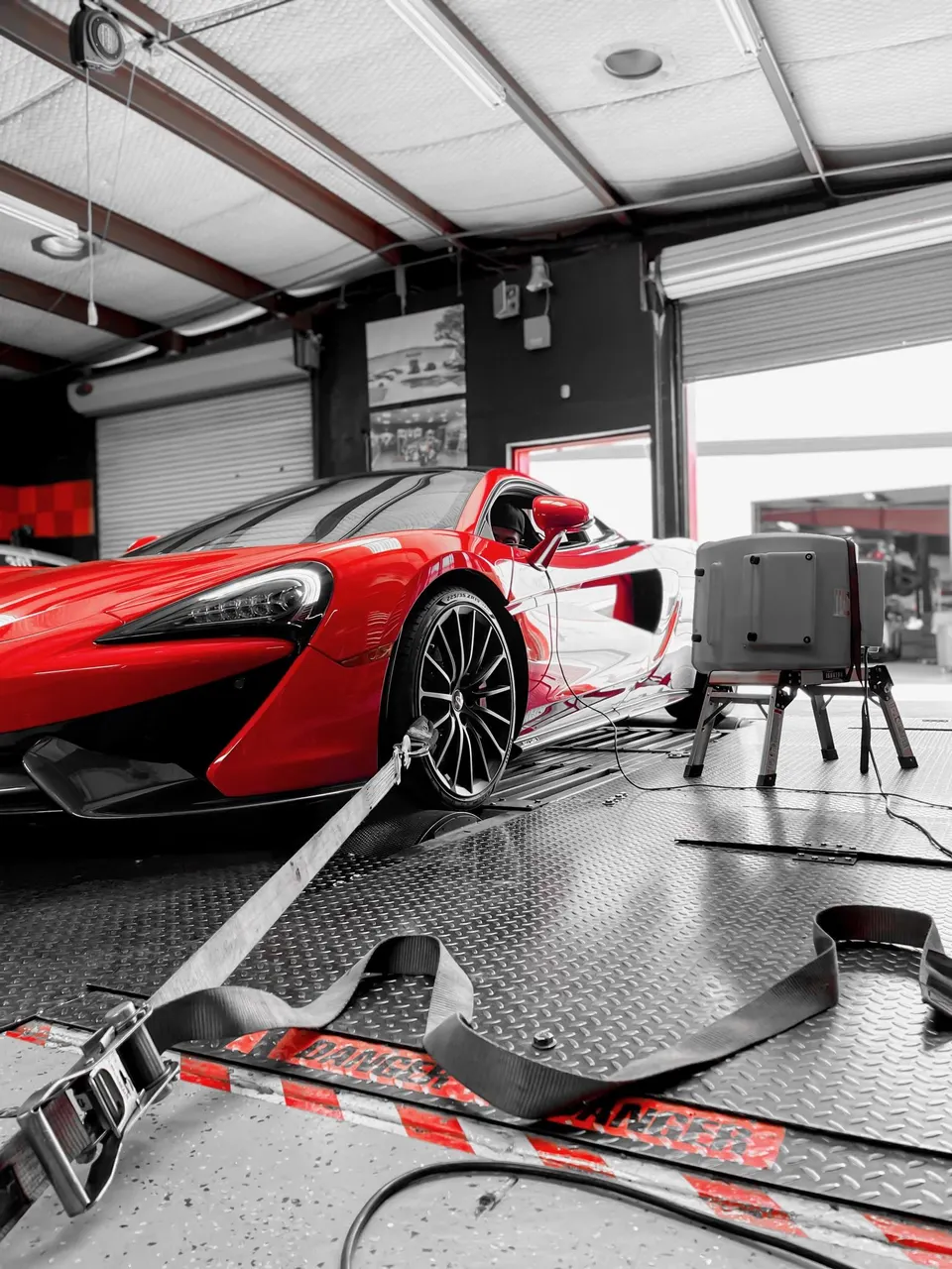 Red McLaren supercar strapped down on a dynamometer for performance testing at Jotech Motorsports.
