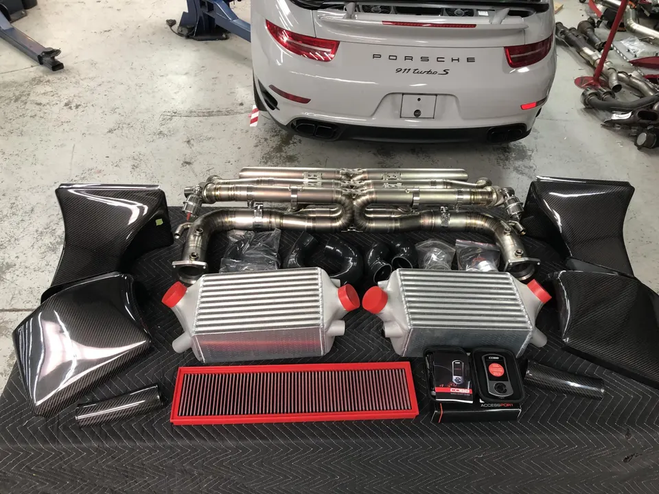 Performance parts including an exhaust system, intercoolers, and carbon fiber intake for a Porsche 911 Turbo S.