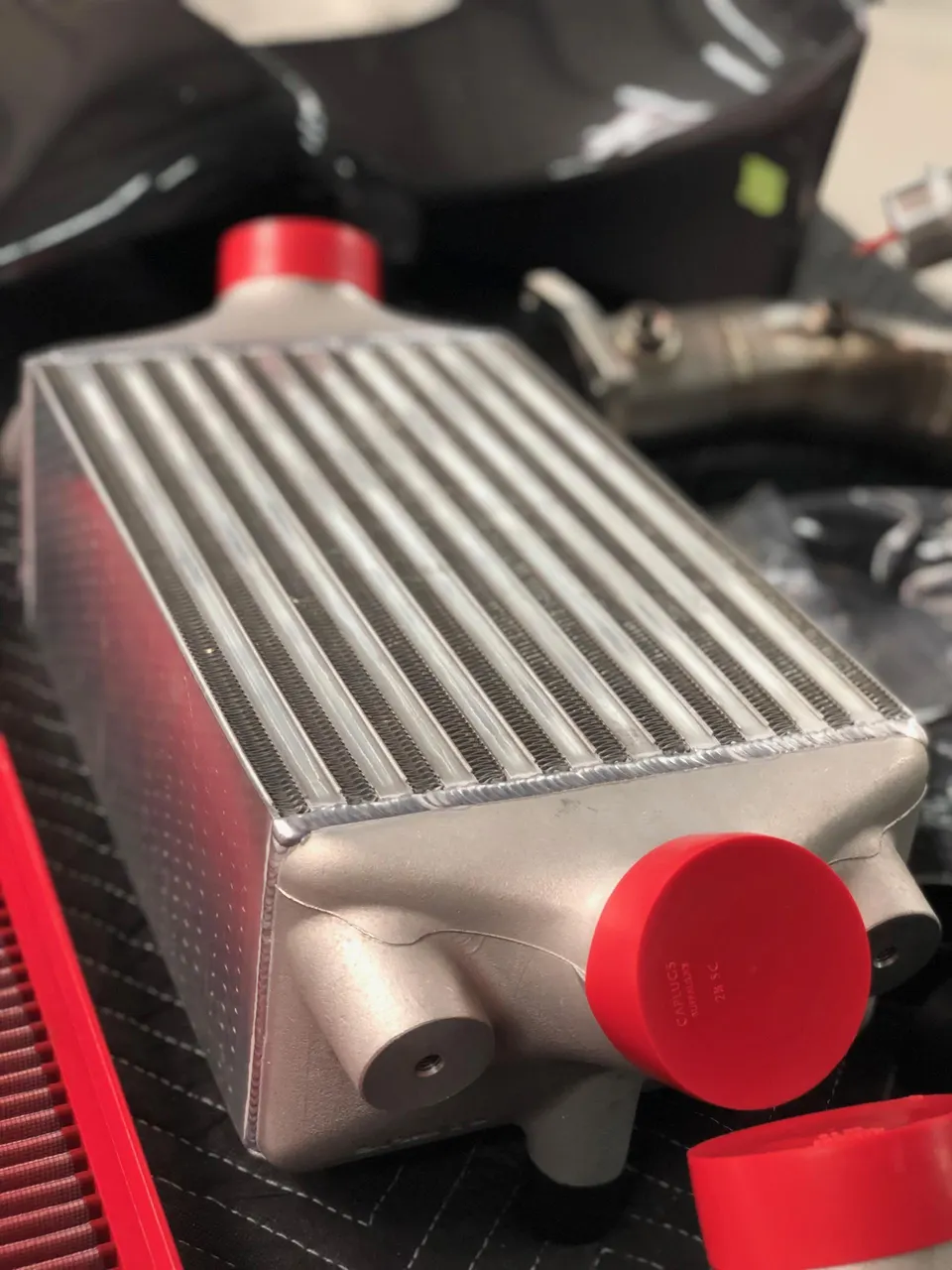 High-performance aluminum intercooler with red protective caps, ready for installation at Jotech Motorsports.