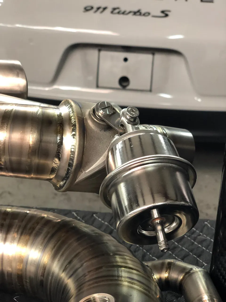 Close-up of a titanium performance exhaust valve and piping for a Porsche 911 Turbo S.