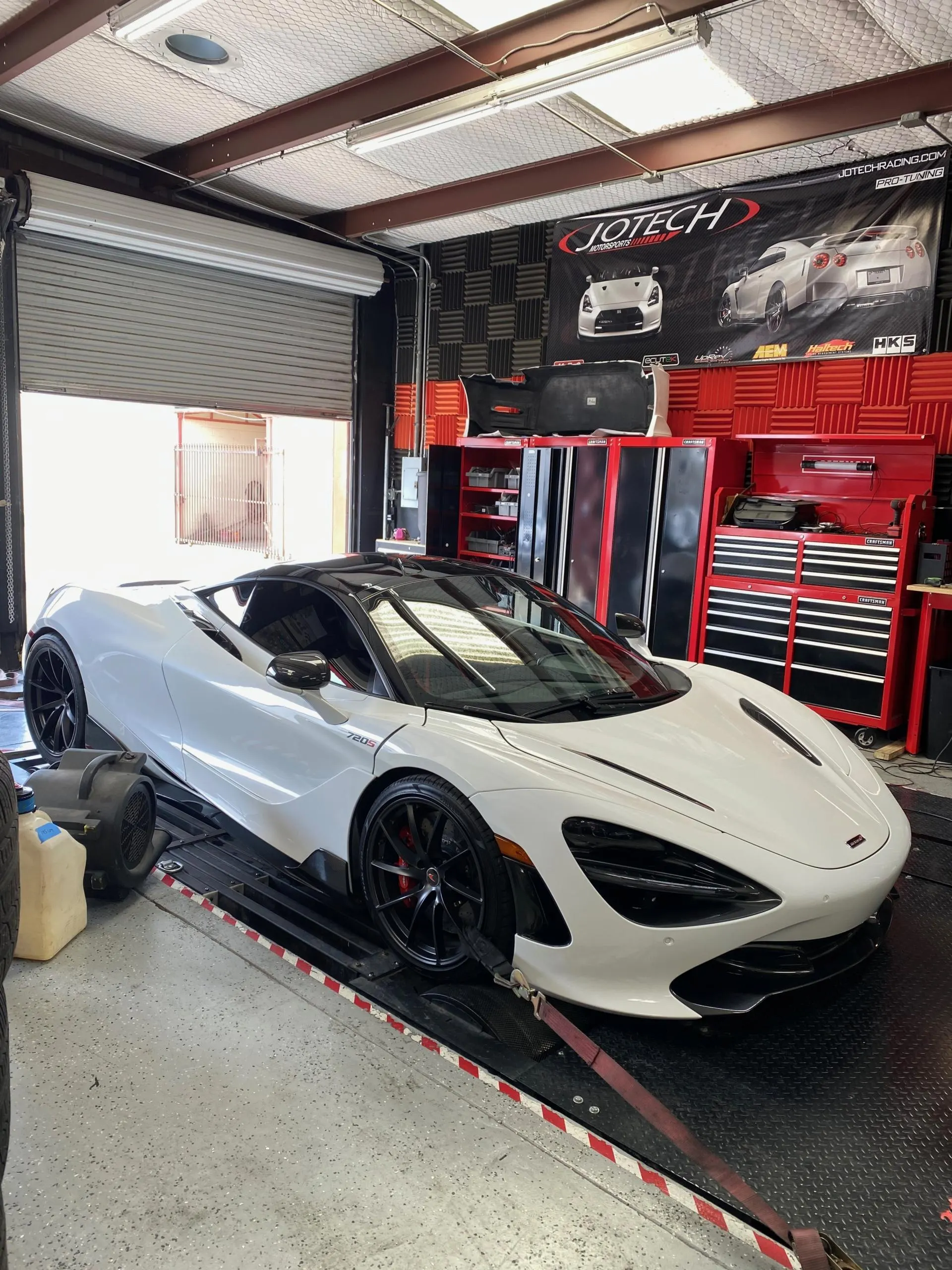 White McLaren 720S strapped to a dynamometer at Jotech Motorsports for performance tuning.