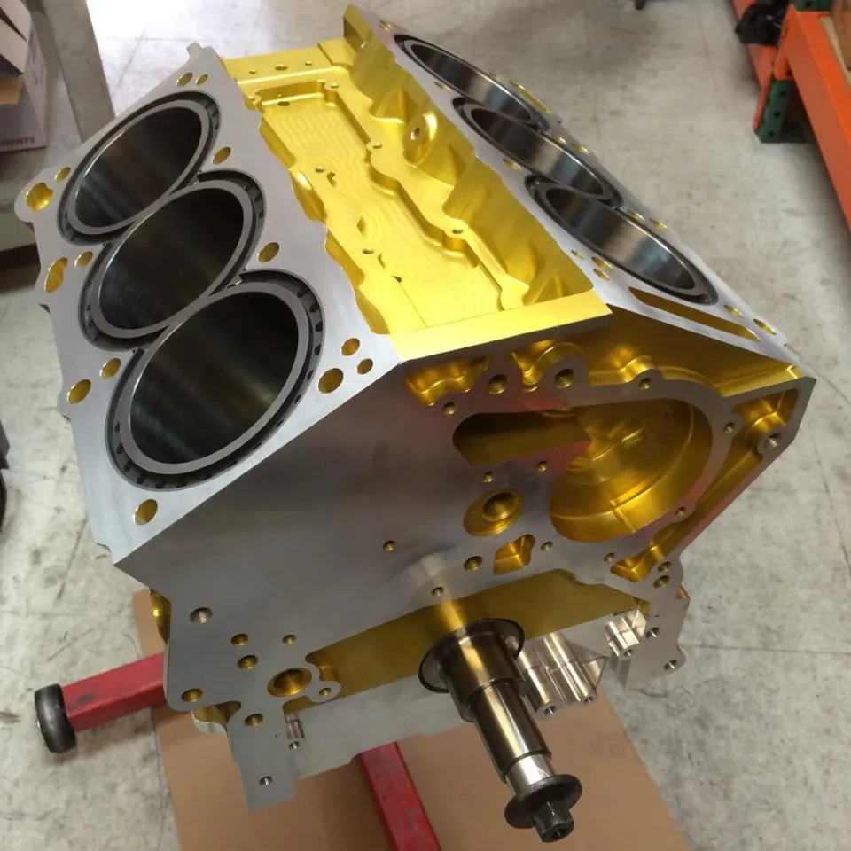 A gold and silver aftermarket engine block on a red engine stand in a workshop.