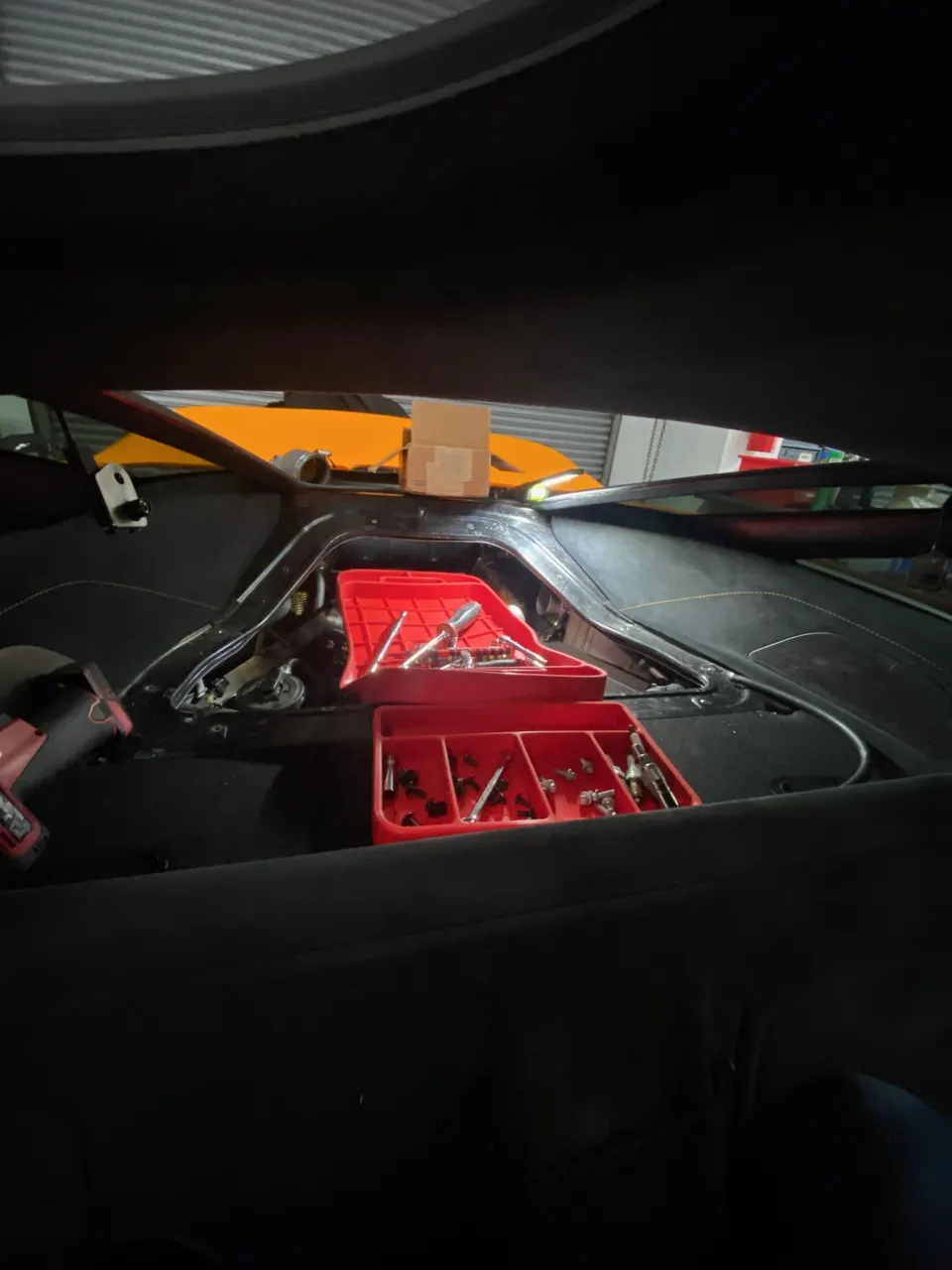 Interior view of a McLaren undergoing work in a shop, with tools and fasteners laid out during disassembly.