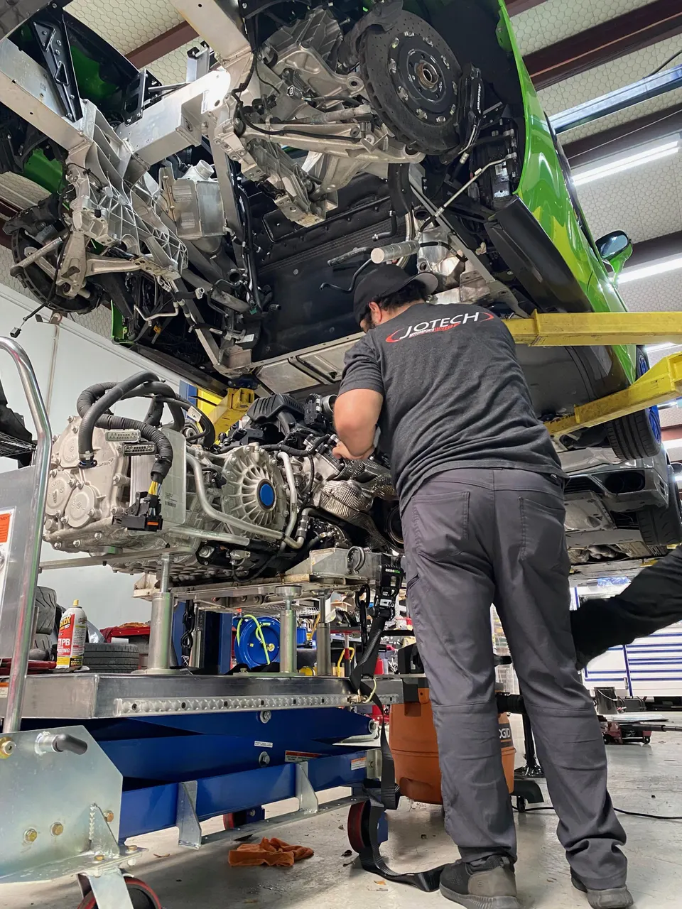 Jotech Motorsports mechanic working on a Lamborghini Huracan engine and transmission assembly removed from the car in the shop.