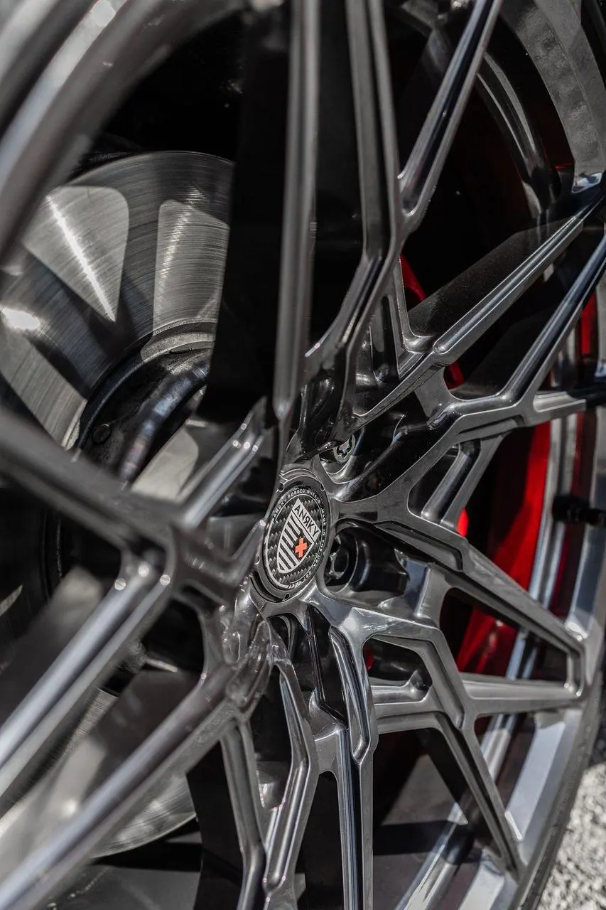 Close-up of an Anrky multi-spoke custom wheel with red brake calipers and a brushed metal rotor.