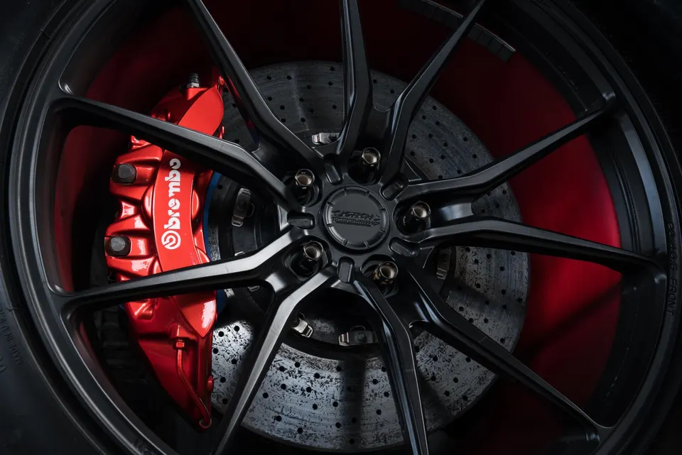 Close-up of a black multi-spoke wheel with a red Brembo brake caliper and drilled rotor.