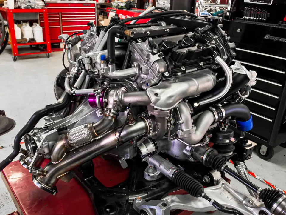 A high-performance engine assembly with twin turbochargers and custom exhaust manifolds in a tuning shop.