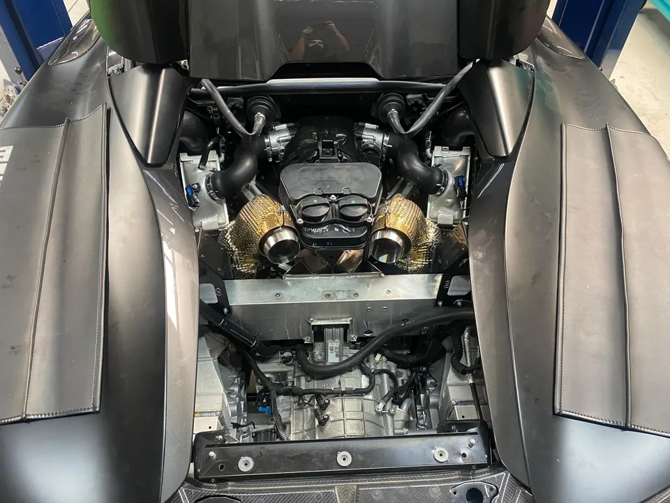 Overhead view of a McLaren engine bay with twin turbochargers and heat shields, showcasing performance upgrades.