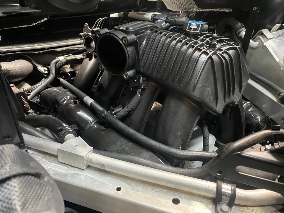 Close-up of a car's engine bay showing the intake manifold and various hoses.