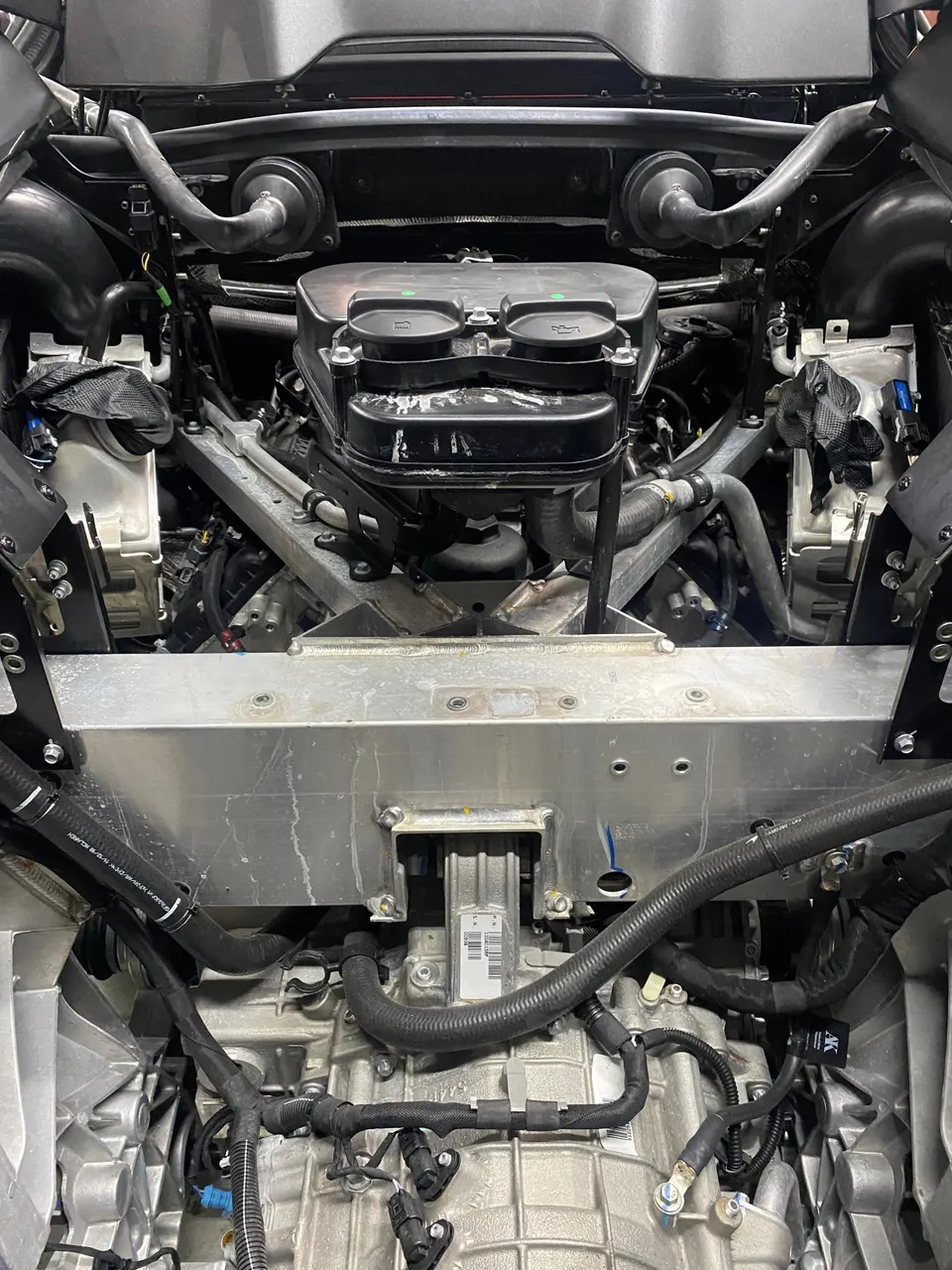 Overhead view of a McLaren engine bay showing the intake manifold, engine, and transmission during a build.