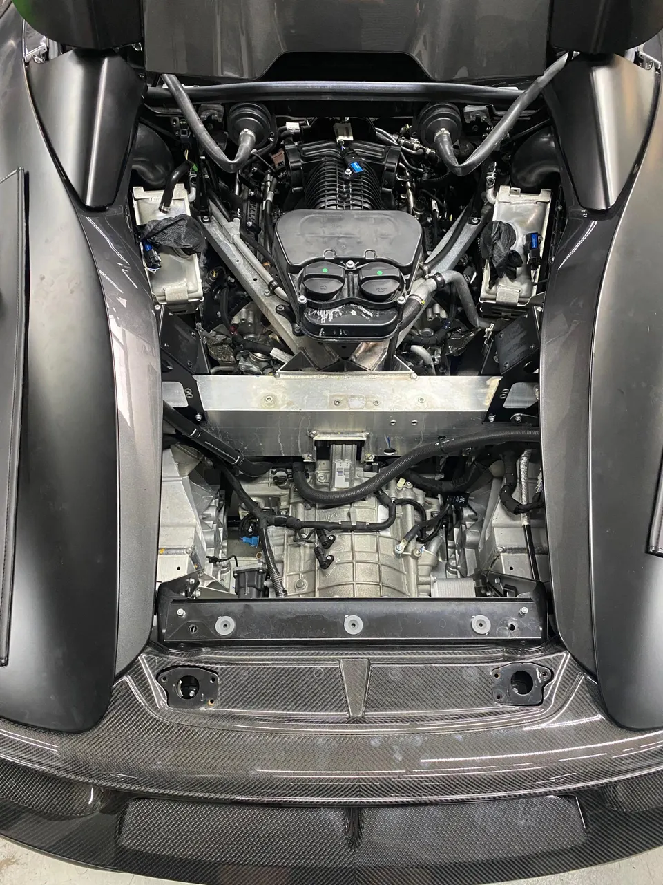 Overhead view of a McLaren engine bay, highlighting the induction system and carbon fiber elements.