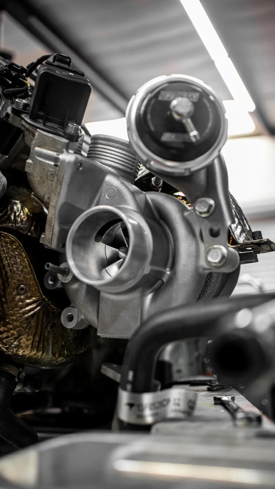 A close-up view of a high-performance turbocharger and wastegate assembly in an engine bay.